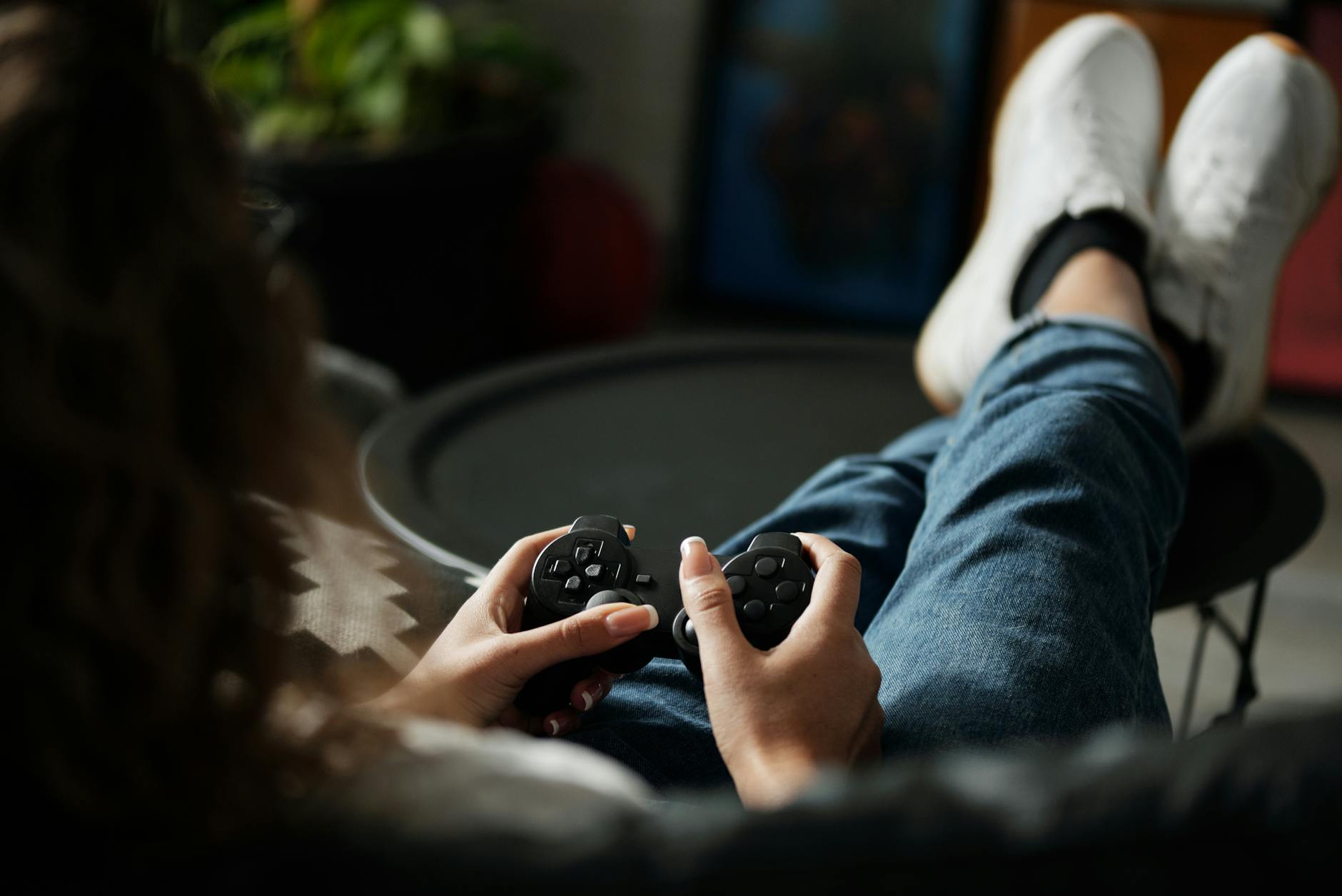 Kobieta gra na PS4 padem, odpoczywając w domu z nogami na stoliku