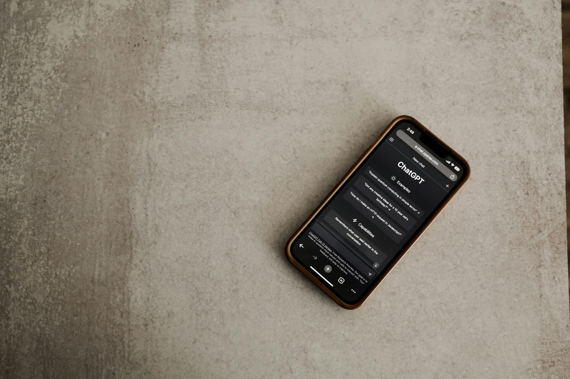 Smartfon z otwartą aplikacją ChatGPT leżący na fakturowanej powierzchni