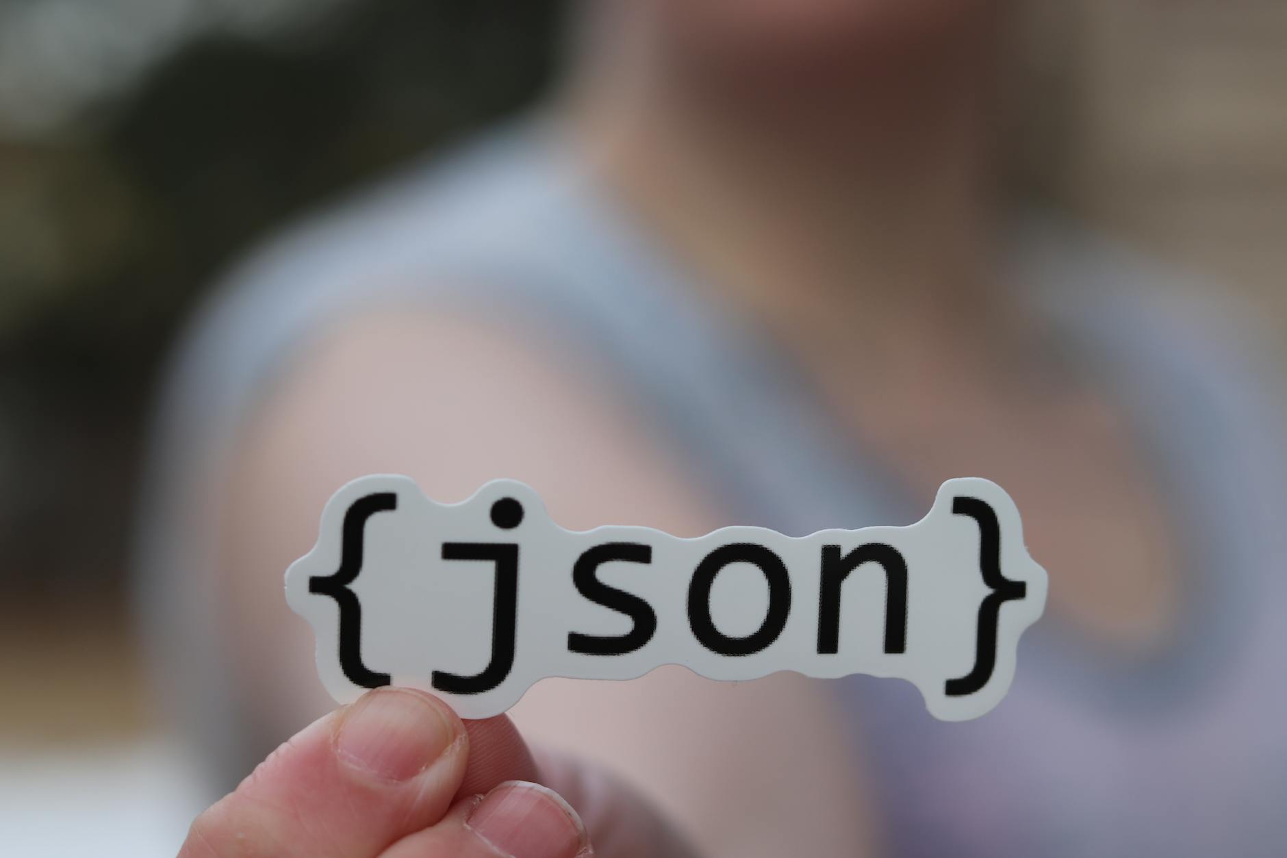 Dłoń trzymająca naklejkę z napisem JSON, symbol rozwoju oprogramowania