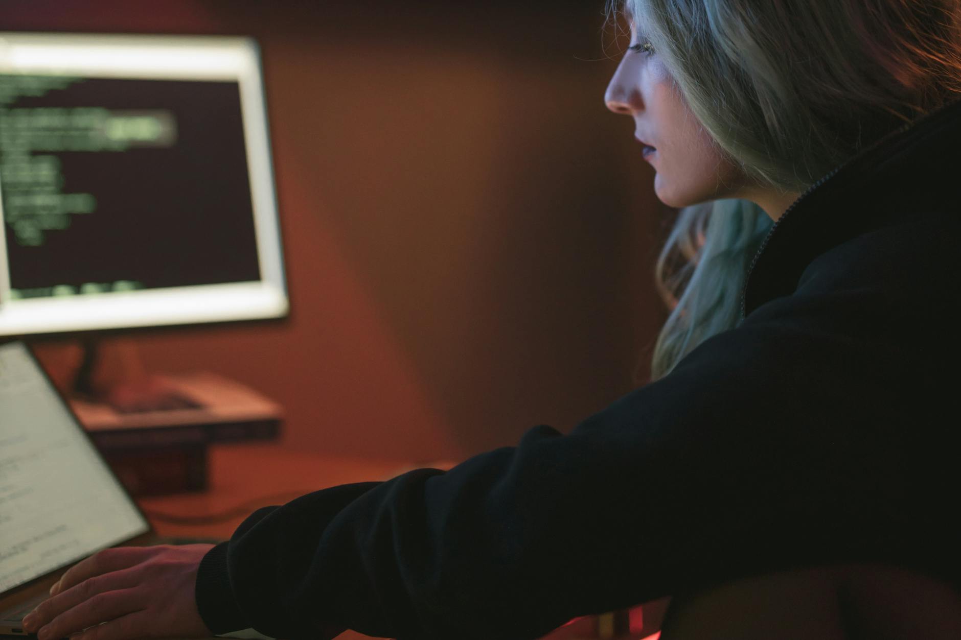 Kobieta nocą programuje na ultrabooku w ciemnym pomieszczeniu