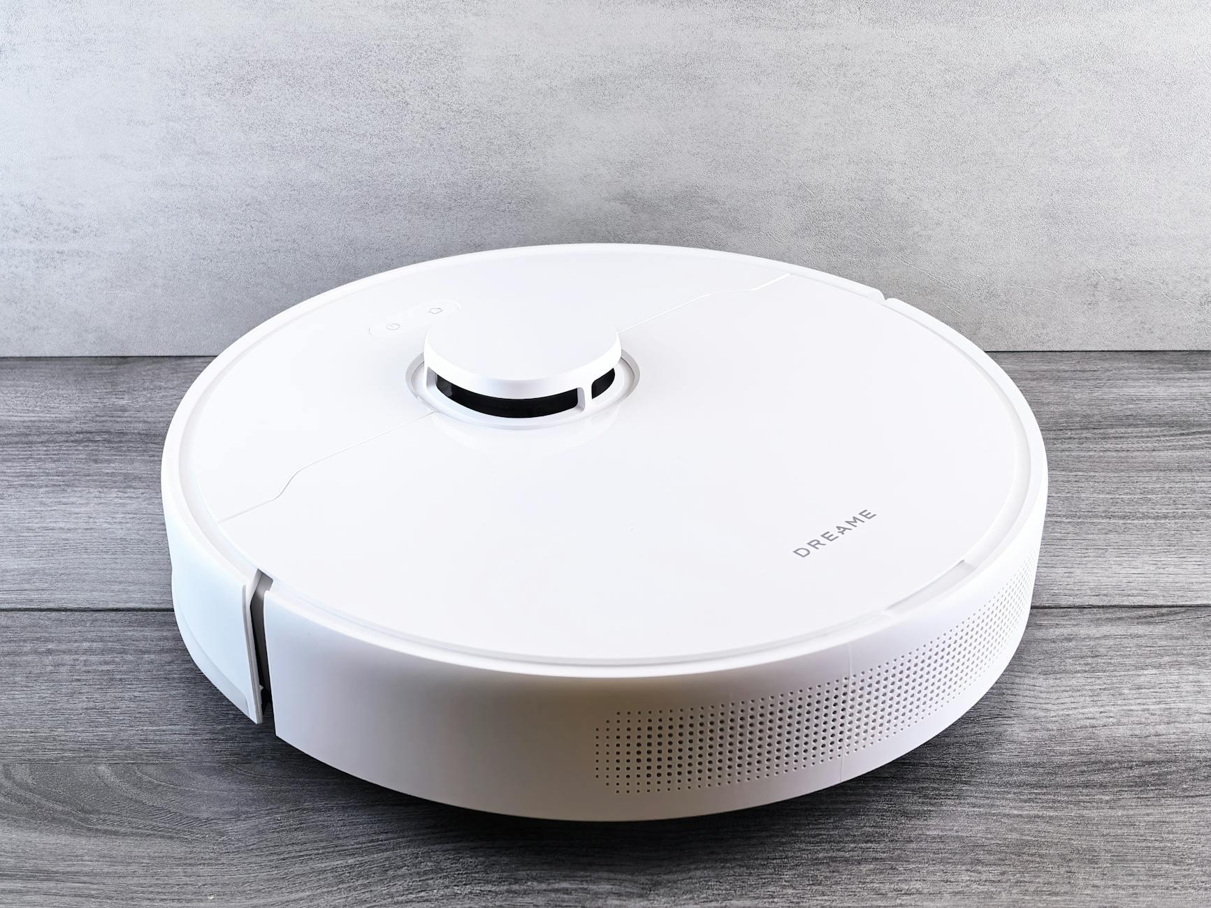 Biały robot odkurzający na drewnianej podłodze w inteligentnym domu
