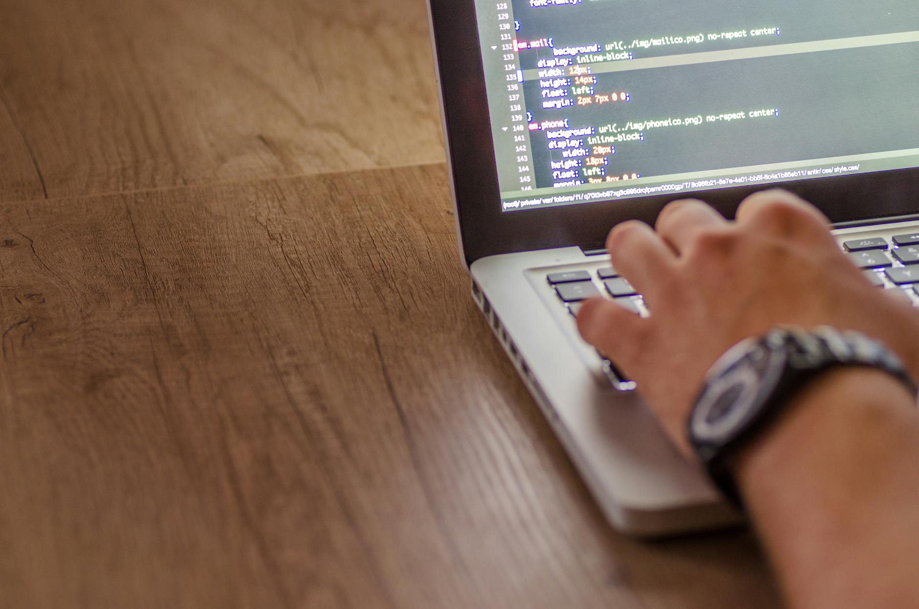Programista piszący kod JavaScript na laptopie podczas pracy nad projektem