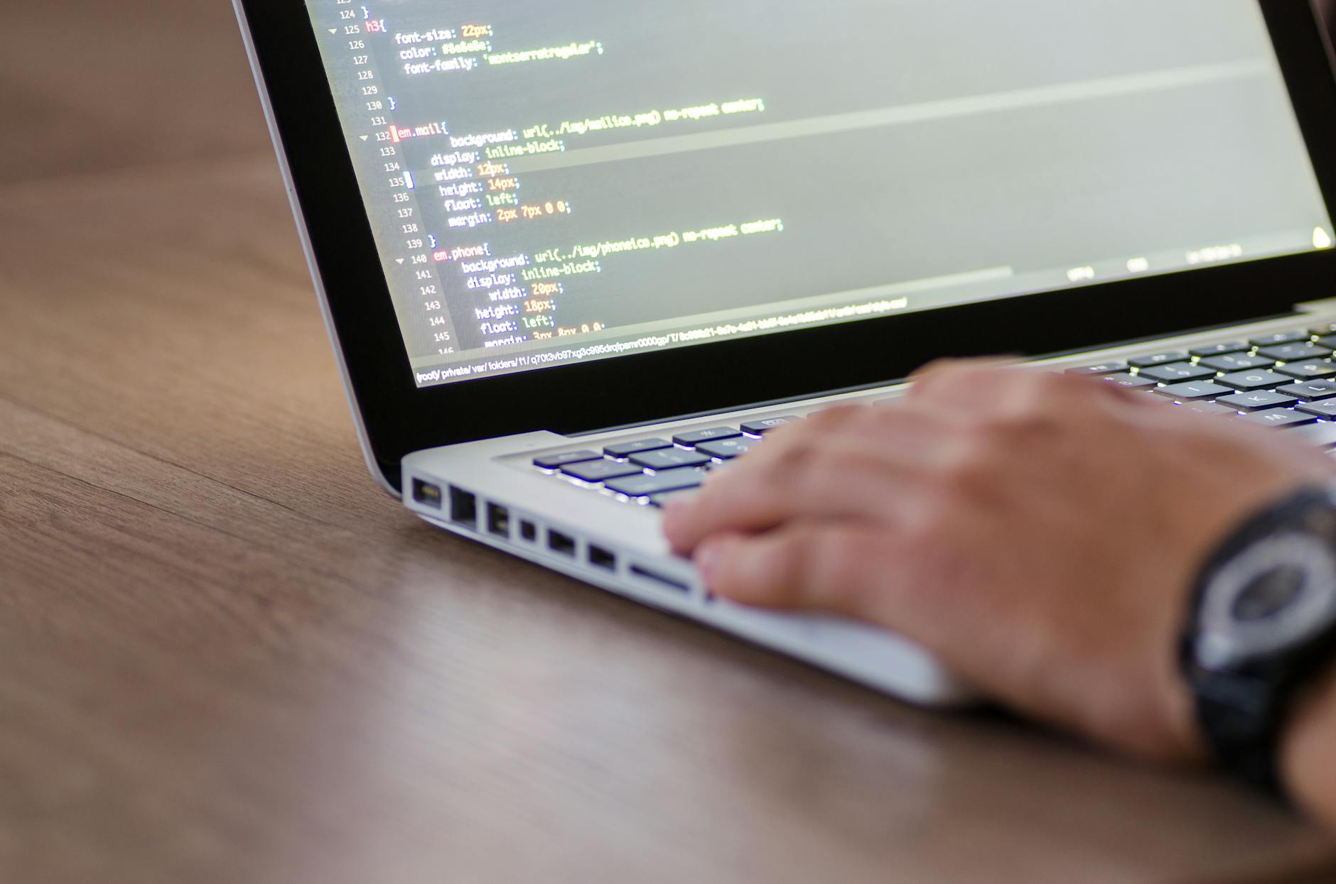 Programista pisze kod HTML na laptopie podczas pracy nad projektem
