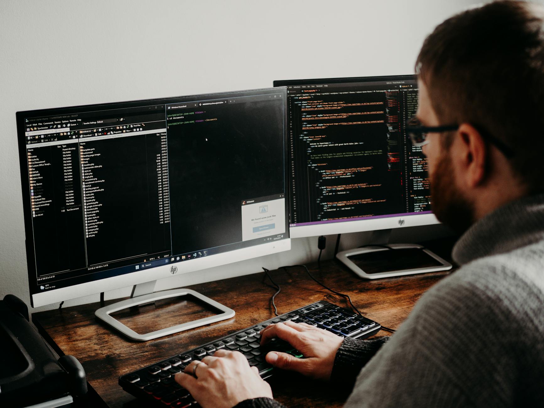Programista przy biurku pisze kod na dwóch monitorach