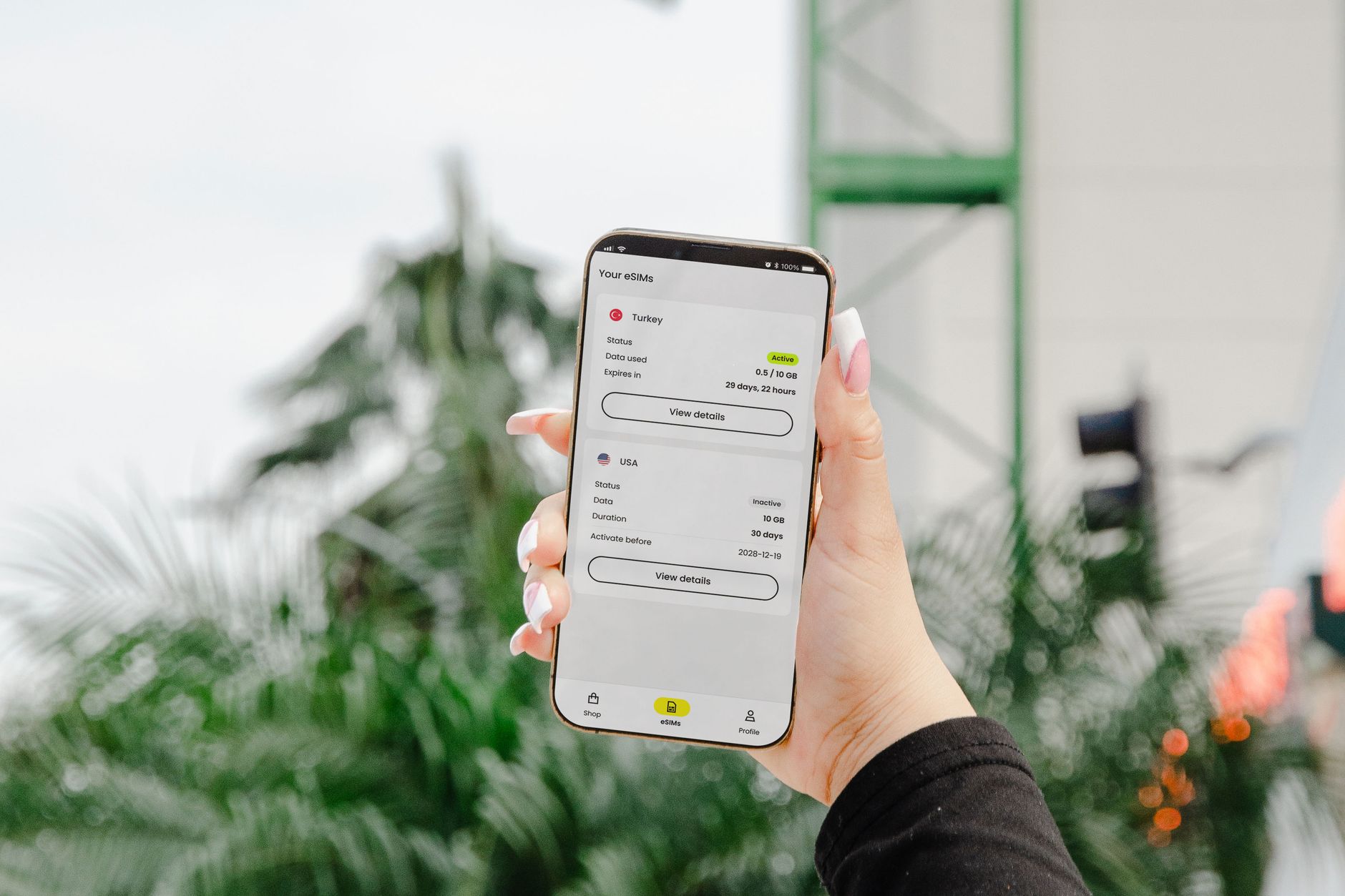 Jak projektować aplikacje mobilne pod 5G: dobre praktyki wydajności i bezpieczeństwa Dłoń kobiety z telefonem pokazującym plany danych eSIM na tle miasta